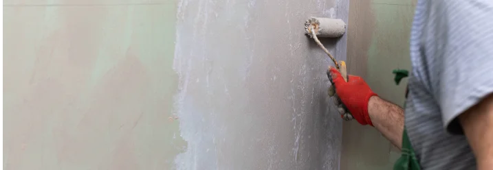 Person grundiert Wand mit Rolle